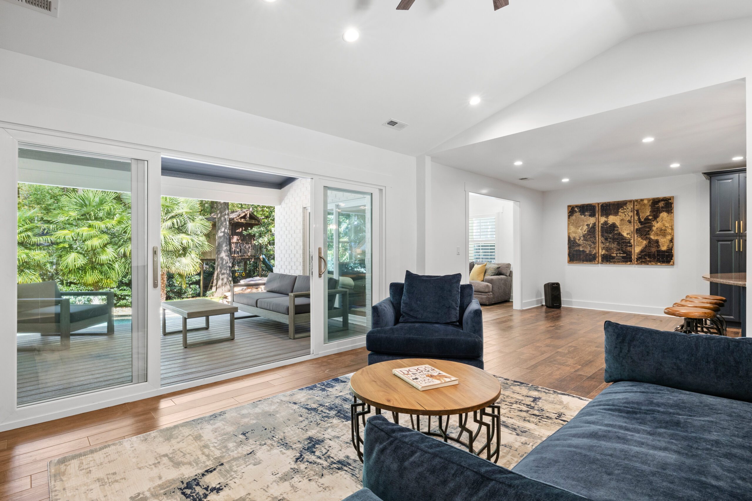 Remodeled modern living room with blue sofas, a round wooden coffee table and a large sliding glass door