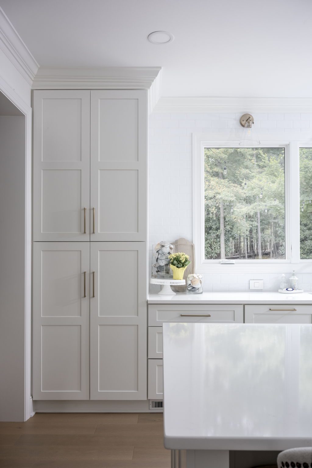 Full-height pantry tower cabinetry with brass hardware and quartz countertops