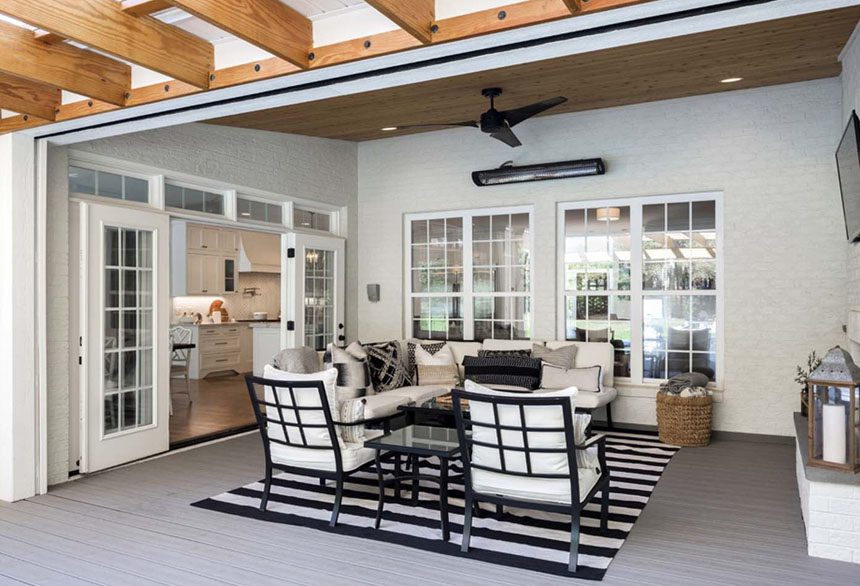Indoor-outdoor sunroom with retractable glass doors, wood ceiling beams and a striped rug